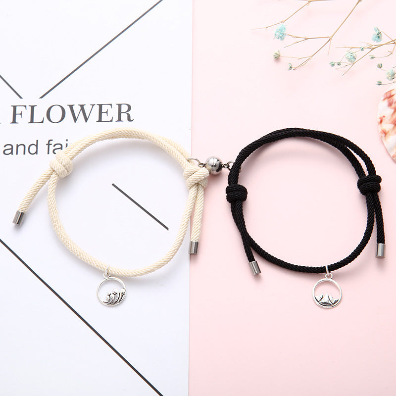 Two New Alloy Eachother Couple Bracelet, one beige and one black, with silver charms on a white and pink background.