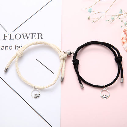 Two New Alloy Eachother Couple Bracelet, one beige and one black, with silver charms on a white and pink background.