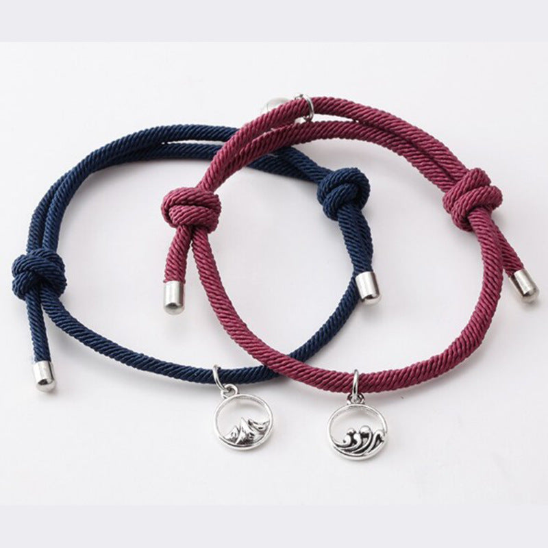 Two braided bracelets, one red and one blue, with silver charms on a white background.