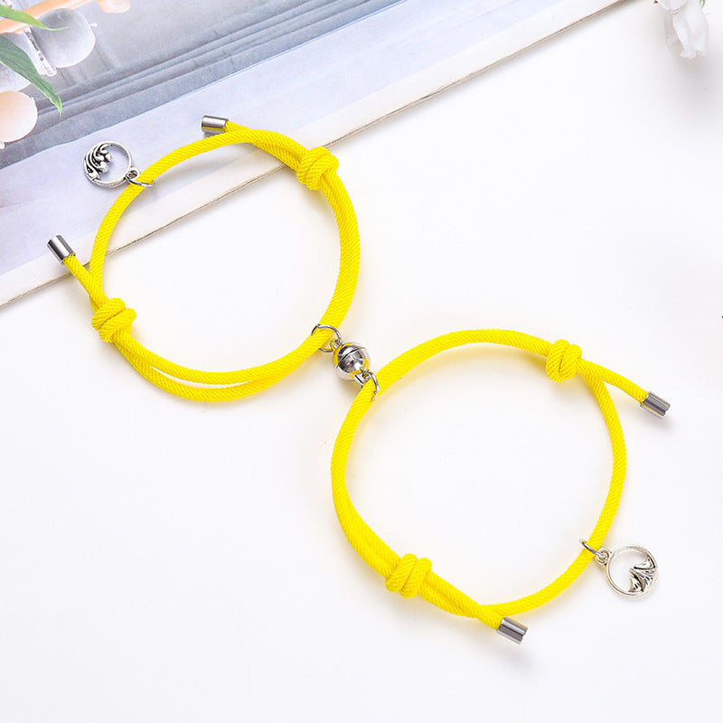 Two yellow bracelets with silver charms on a white surface